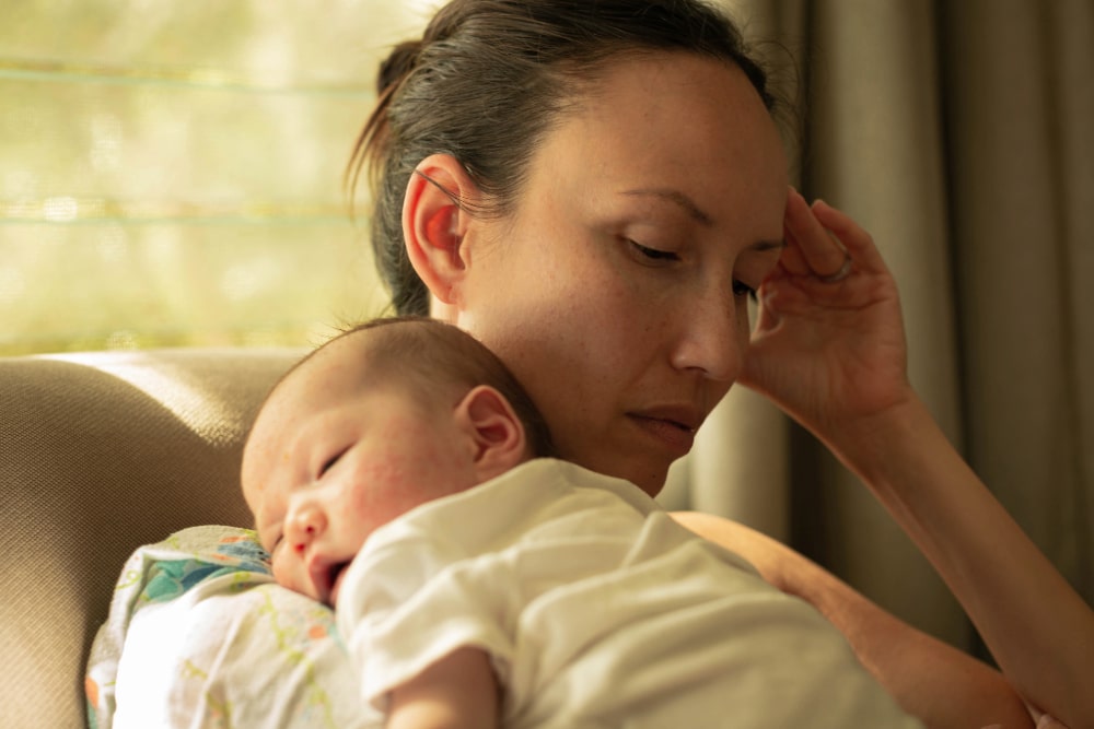 A unhappy mother suffering from postpartum depression, holding her baby.