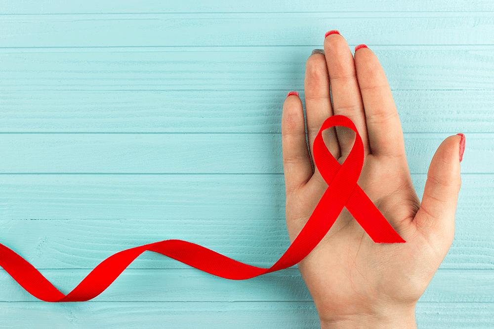 HIV and AIDS awareness ribbon on a hand.